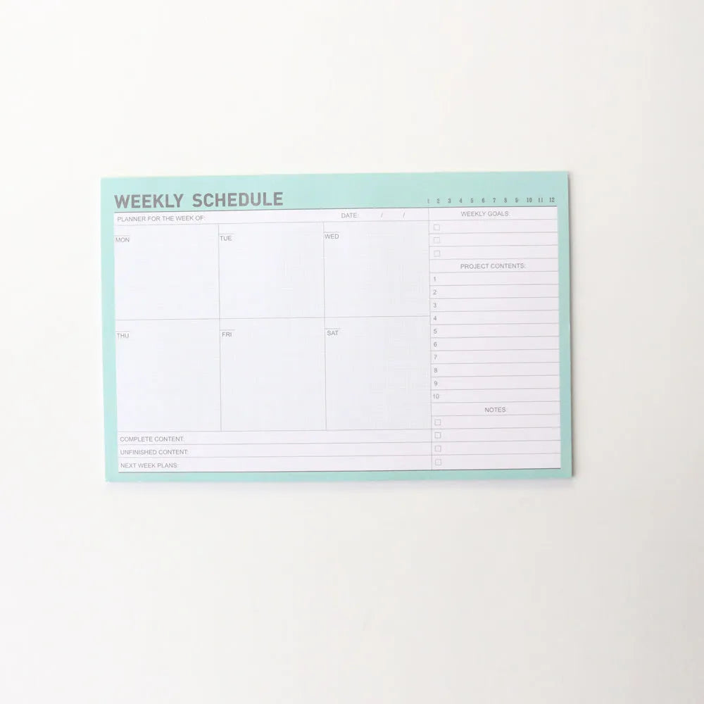Student desk organiser pad notebook with pink and green cover, open to show A4 monthly and A5 weekly planning inserts.