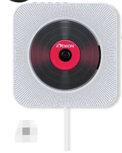 Wall-mounted white CD and DVD player with a digital display and remote control on a table.