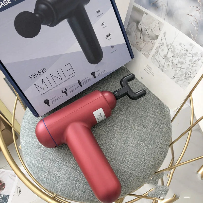 Black fascia gun muscle massager with USB charging port on a grey background.