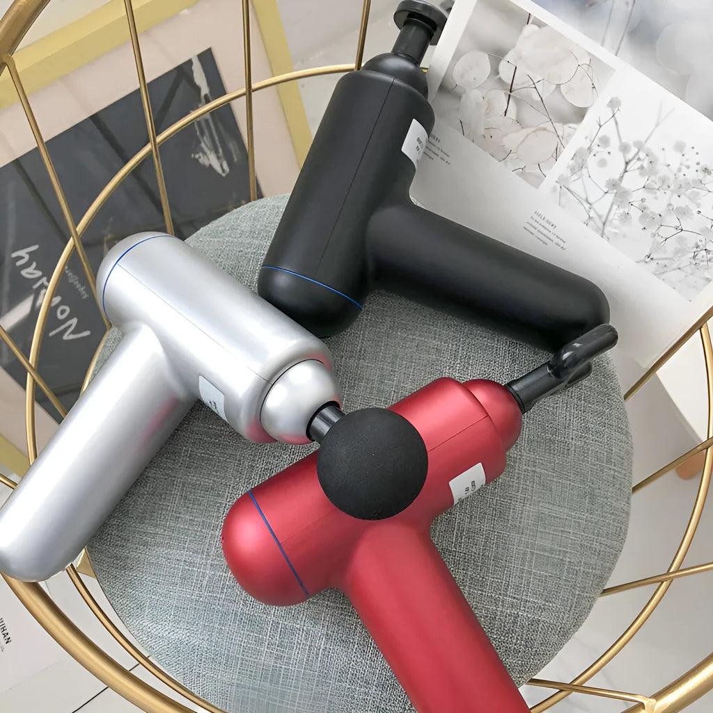 Black fascia gun muscle massager with USB charging port on a grey background.