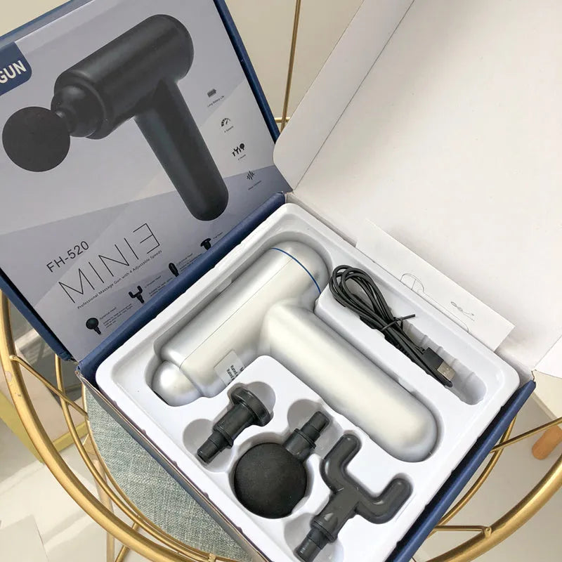 Black fascia gun muscle massager with USB charging port on a grey background.