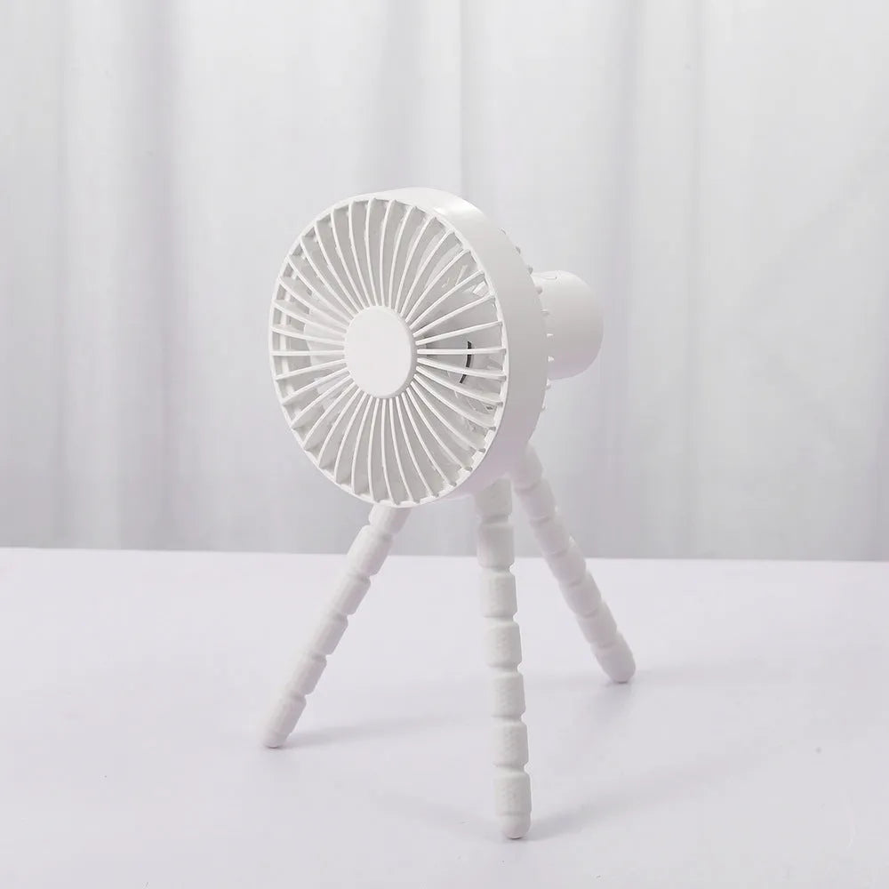 Small adjustable tripod desktop fan with bending head, shown in black on a desk.