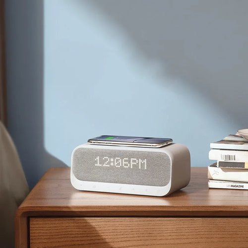 Anker Soundcore white or pink Bluetooth speaker alarm clock with wireless charging pad on top.