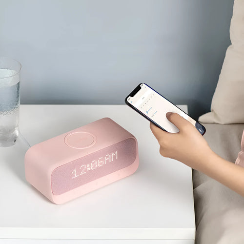 Anker Soundcore white or pink Bluetooth speaker alarm clock with wireless charging pad on top.
