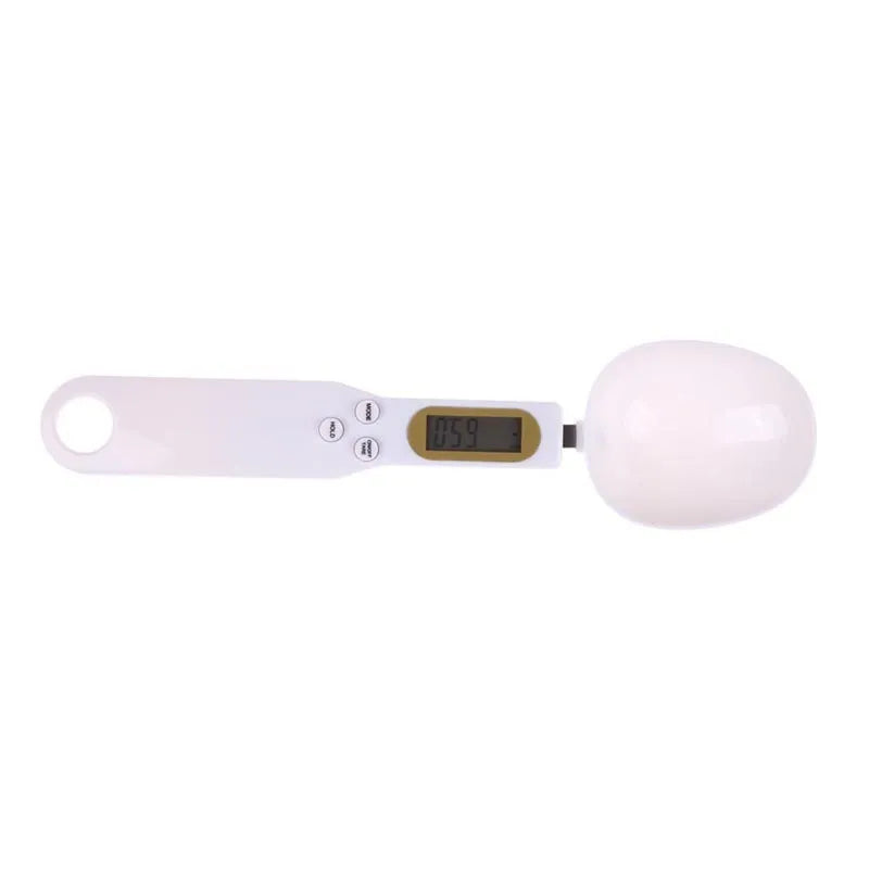 White digital kitchen spoon scale with LCD display showing 0.0g on a wooden table