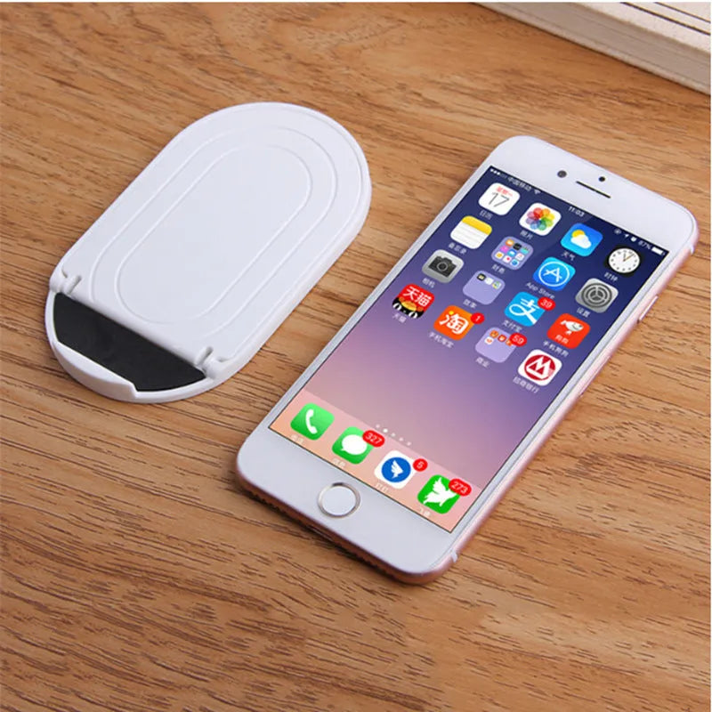 Plastic mobile phone stand with lazy bracket design in assorted colours on a desk.