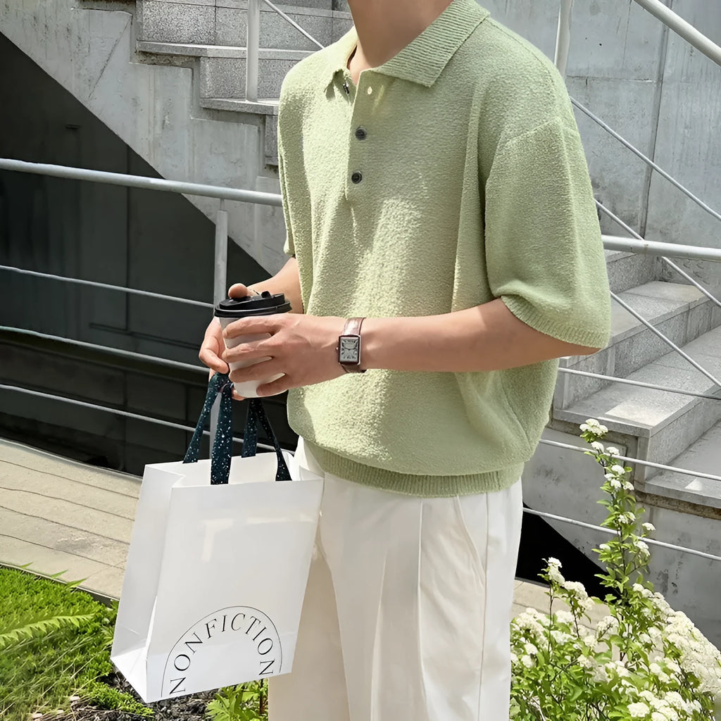 Man wearing a caramel coloured loose fit knitted polo shirt with short sleeves and an asymmetric design.