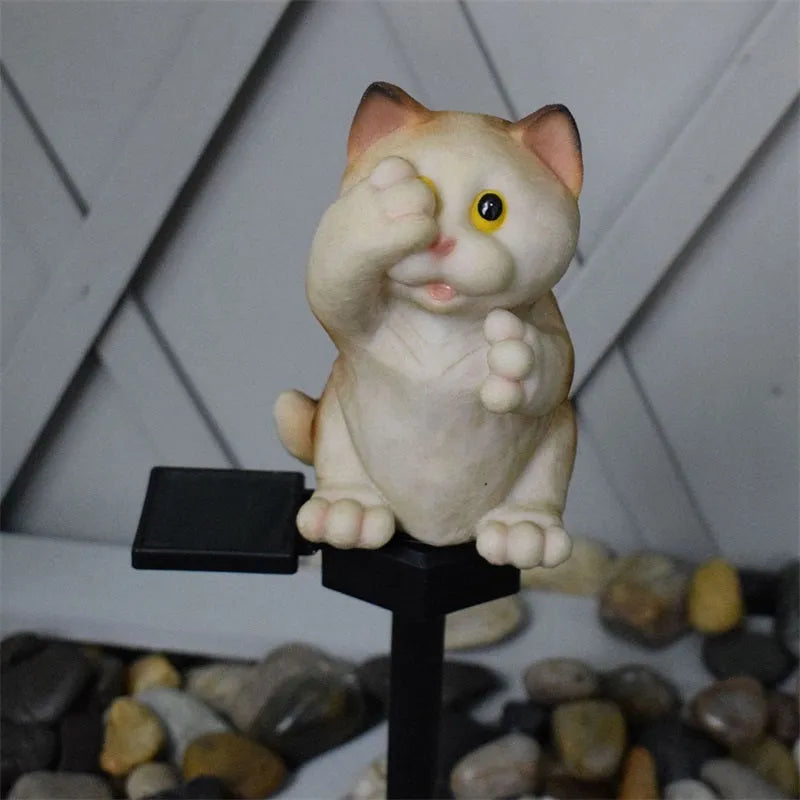 Brown resin solar-powered cat lawn light with LED illumination in a garden setting.