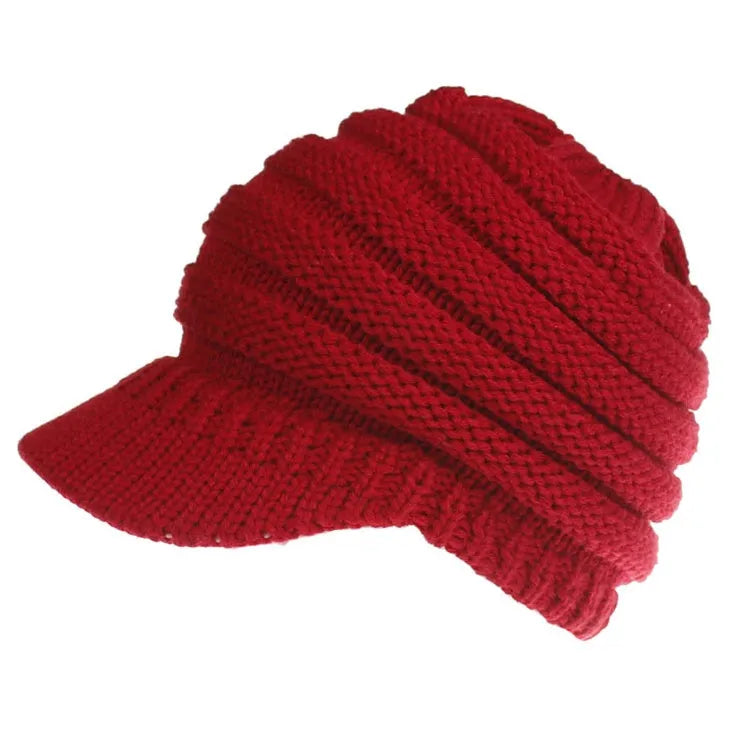 Woman wearing a thick knitted beanie with her ponytail pulled through the hole in the crown.