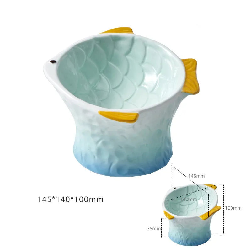 Blue fish-shaped ceramic cat bowl with tilted angle and elevated base on a table.
