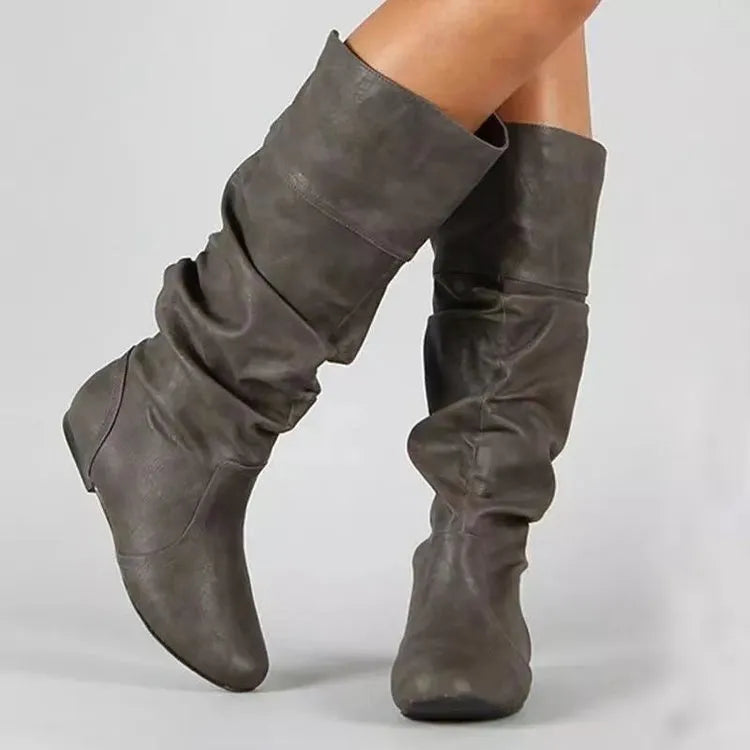 Women's flat ankle boots in black with round toe, high cylinder shaft, slip-on design and rubber sole.