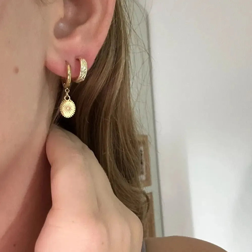 A pair of stainless steel ellipse-shaped button earrings for women on a plain background.