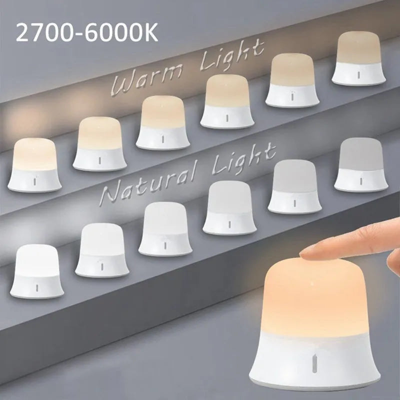 White bedside night light with touch controls for dimming and changing RGB colours on a table.