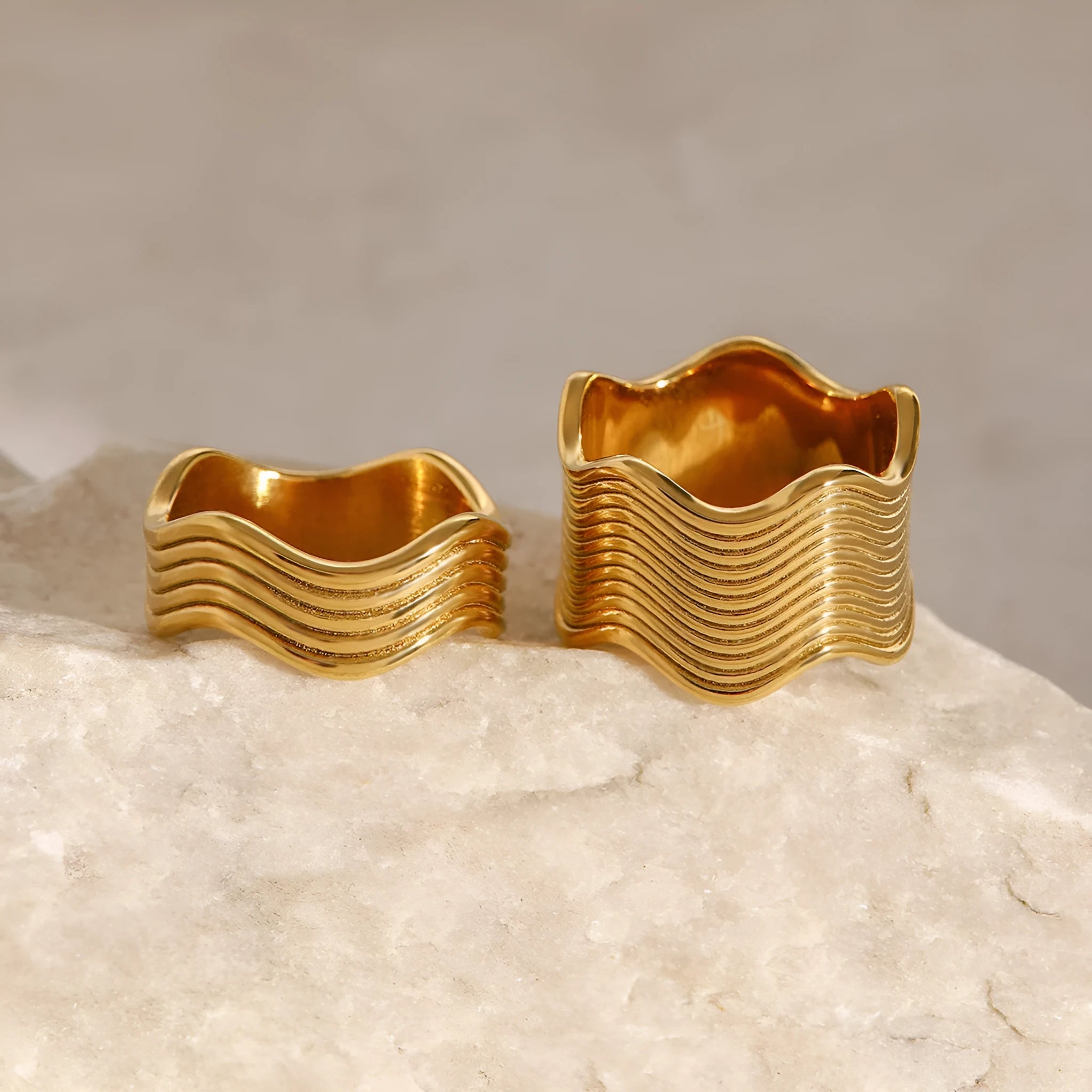 Stainless steel women's ring with wide geometric wave design in silver or rose gold tone.
