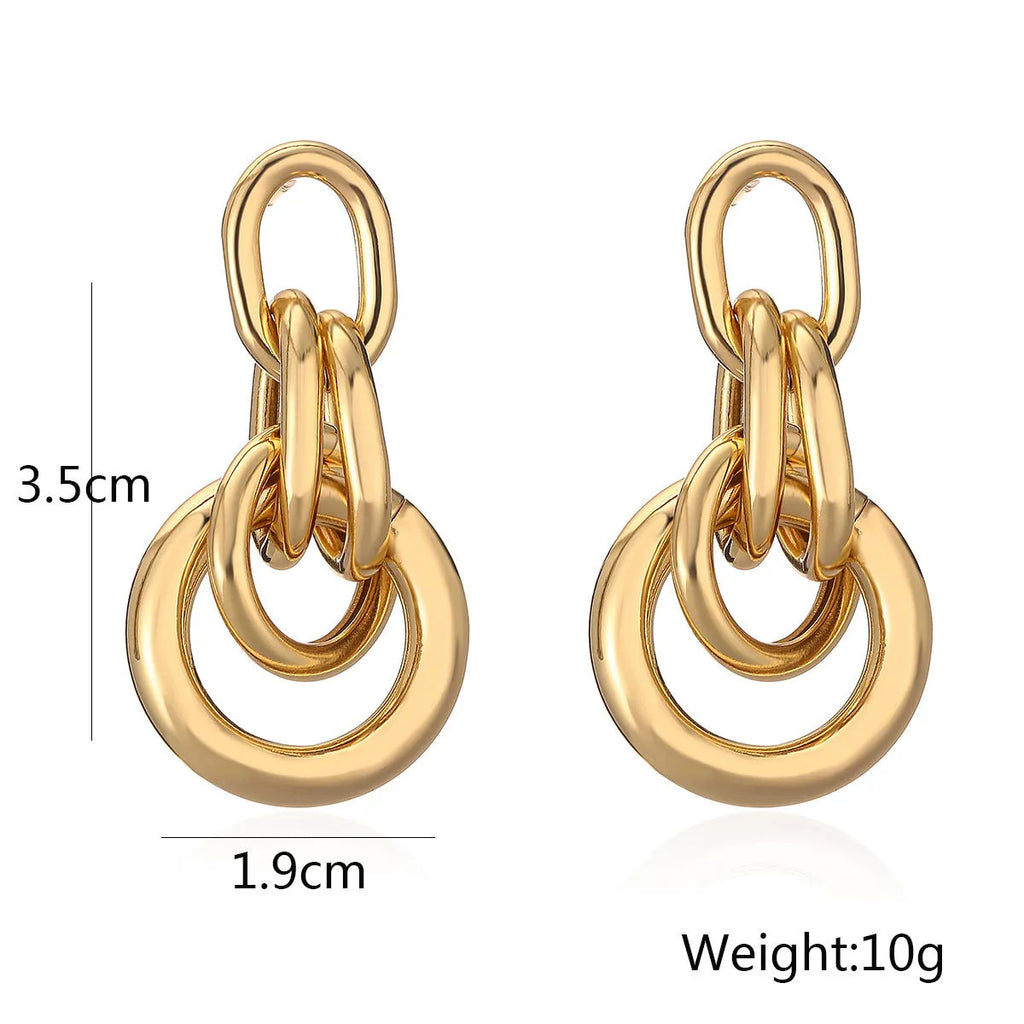 A pair of gold-coloured geometric earrings with an irregular shape on a white background.