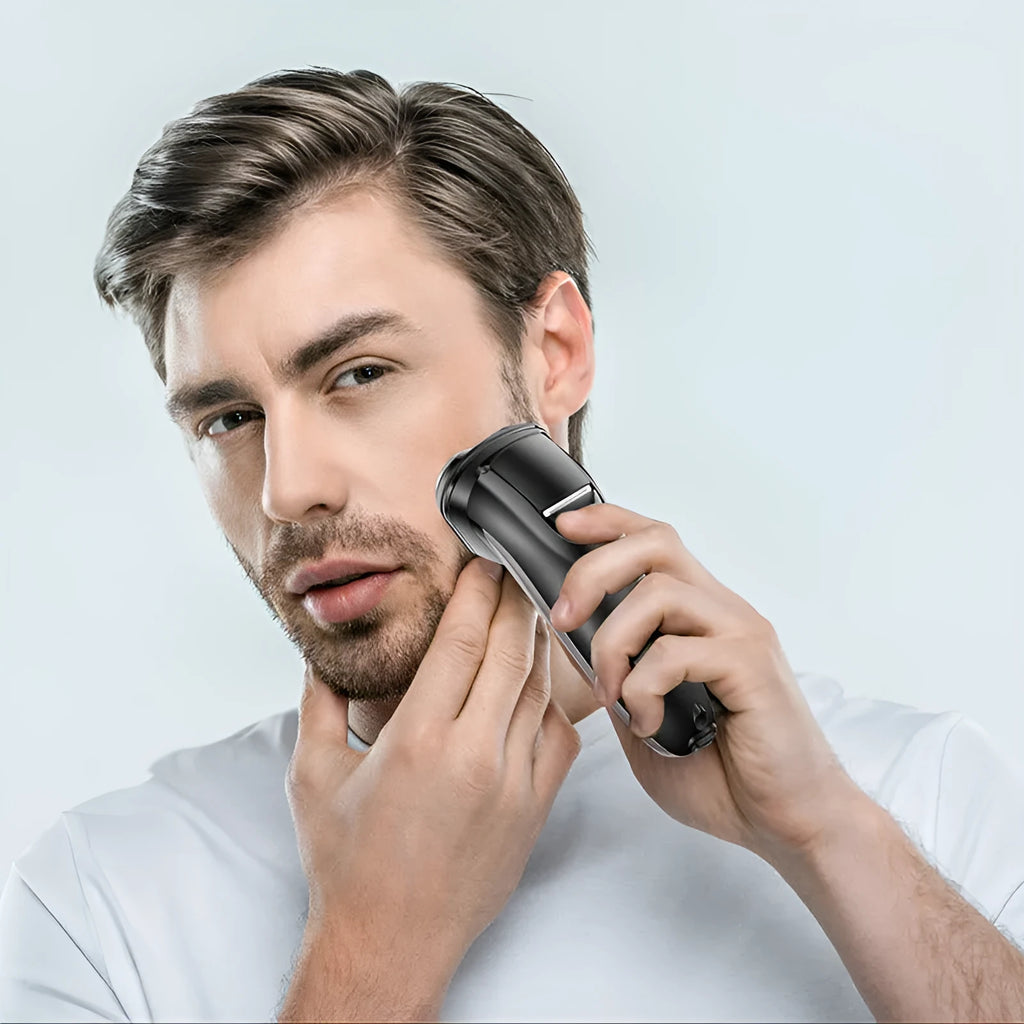 Black electric shaver with three rotating heads, pop-up sideburn trimmer, USB charging cable, and cleaning brush on a grey background.