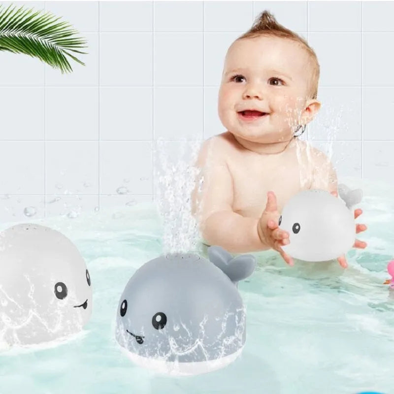White and blue automatic whale bath toy spraying water with LED lights on, placed in a baby bath.