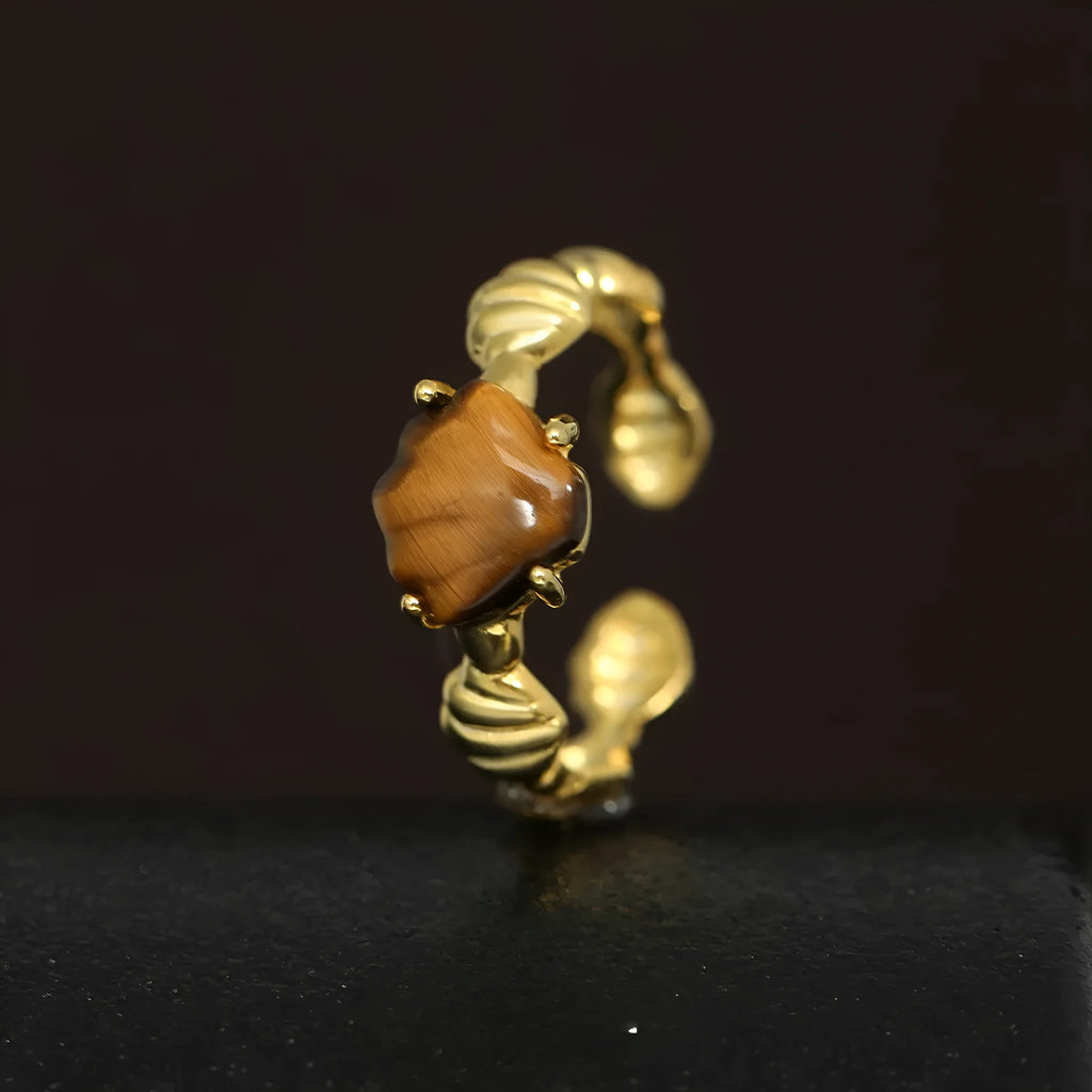 Adjustable silver ring featuring a carved shell and tiger eye stone design in a choice of finishes.