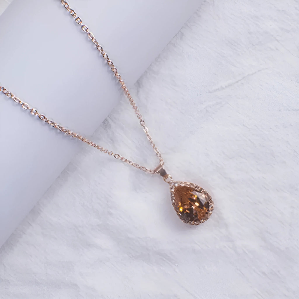 Water drop shaped geometric pendant necklace with rhinestone detailing in rose gold pink colour