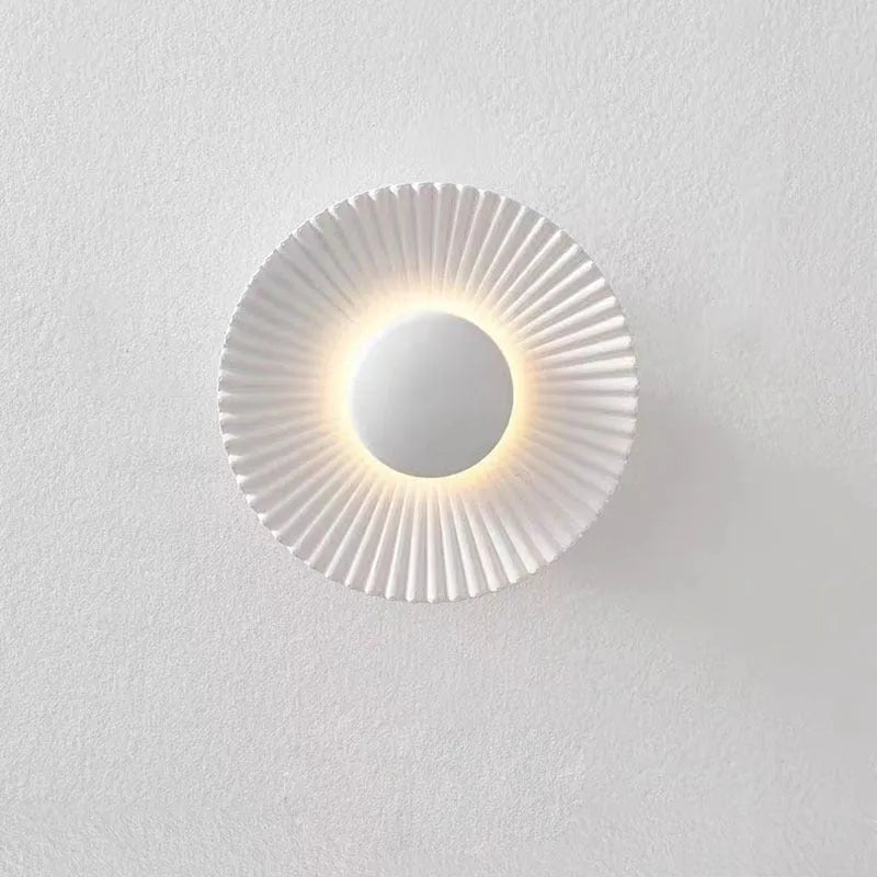 Round wall lamp with aluminium shade in a two-tone white and gold colour combination, mounted on a plain wall.