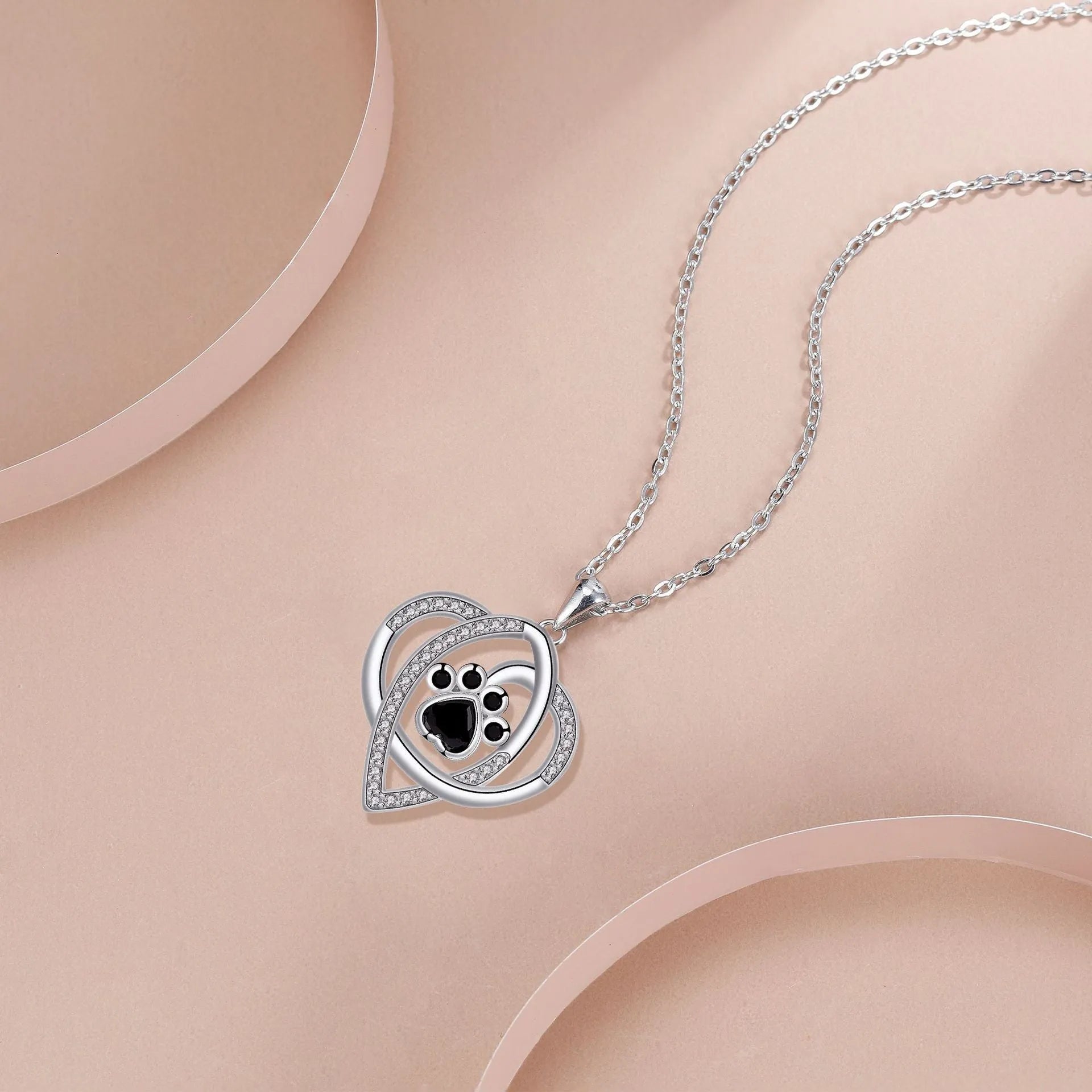 Close-up of dog and cat paw print pendant necklace with cross chain
