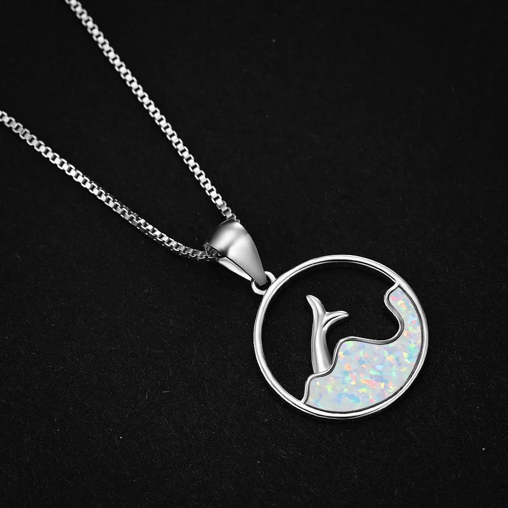 White gold geometric sea fishtail pendant necklace with a round blue opal stone on a chain.