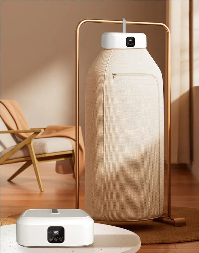 White cylindrical foldable laundry dryer with remote control on a table.