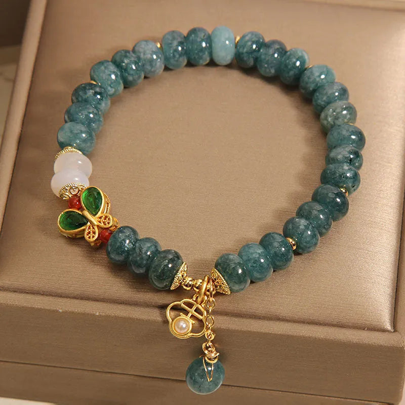 Blue water jade abacus beads bracelet with white agate, butterfly motifs and rhinestone accents on alloy band