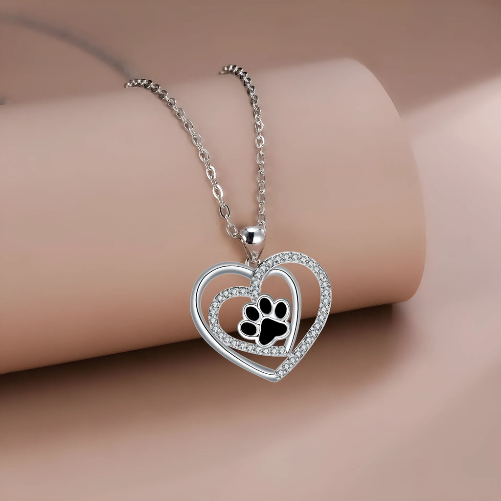 Gold tone dog paw print and heart charm necklace on a cross chain for women.