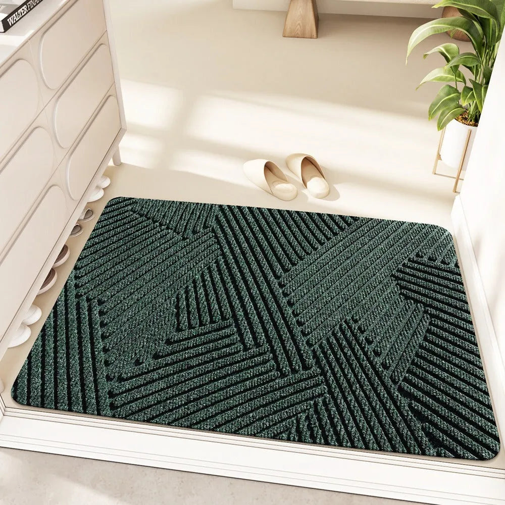 Green alien-shaped entrance mat with cartoon pattern on a wooden floor.