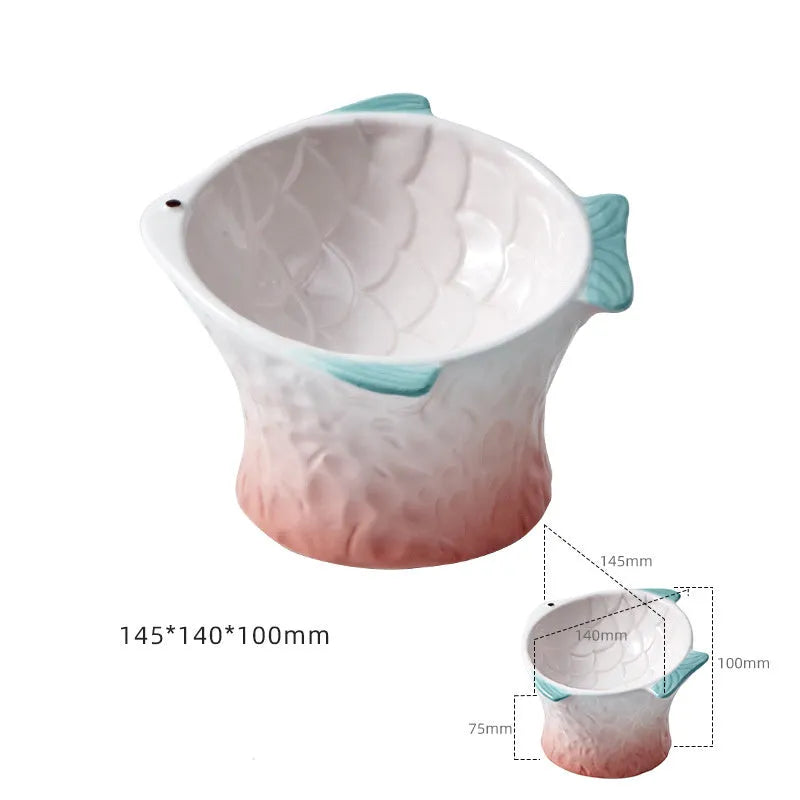 Blue fish-shaped ceramic cat bowl with tilted angle and elevated base on a table.