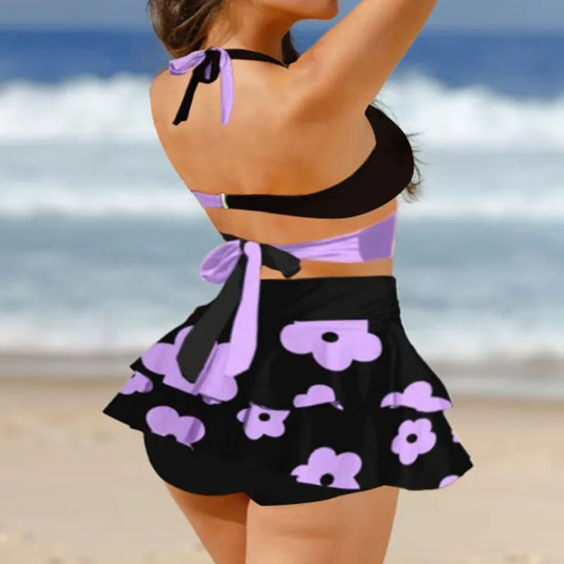 Women's black bikini set with lace-up detail and matching split skirt laid flat.