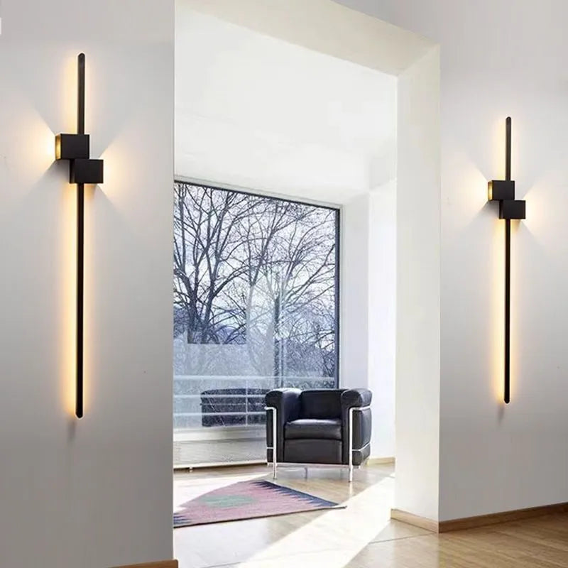 Modern minimalist wall lamp black 80cm length installed above a bedside table with warm low-voltage light