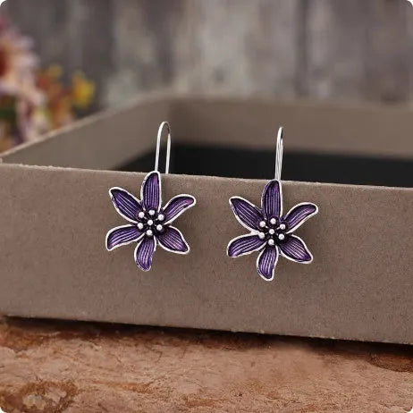 A pair of purple flower-shaped alloy drop earrings with a retro design on a white background.