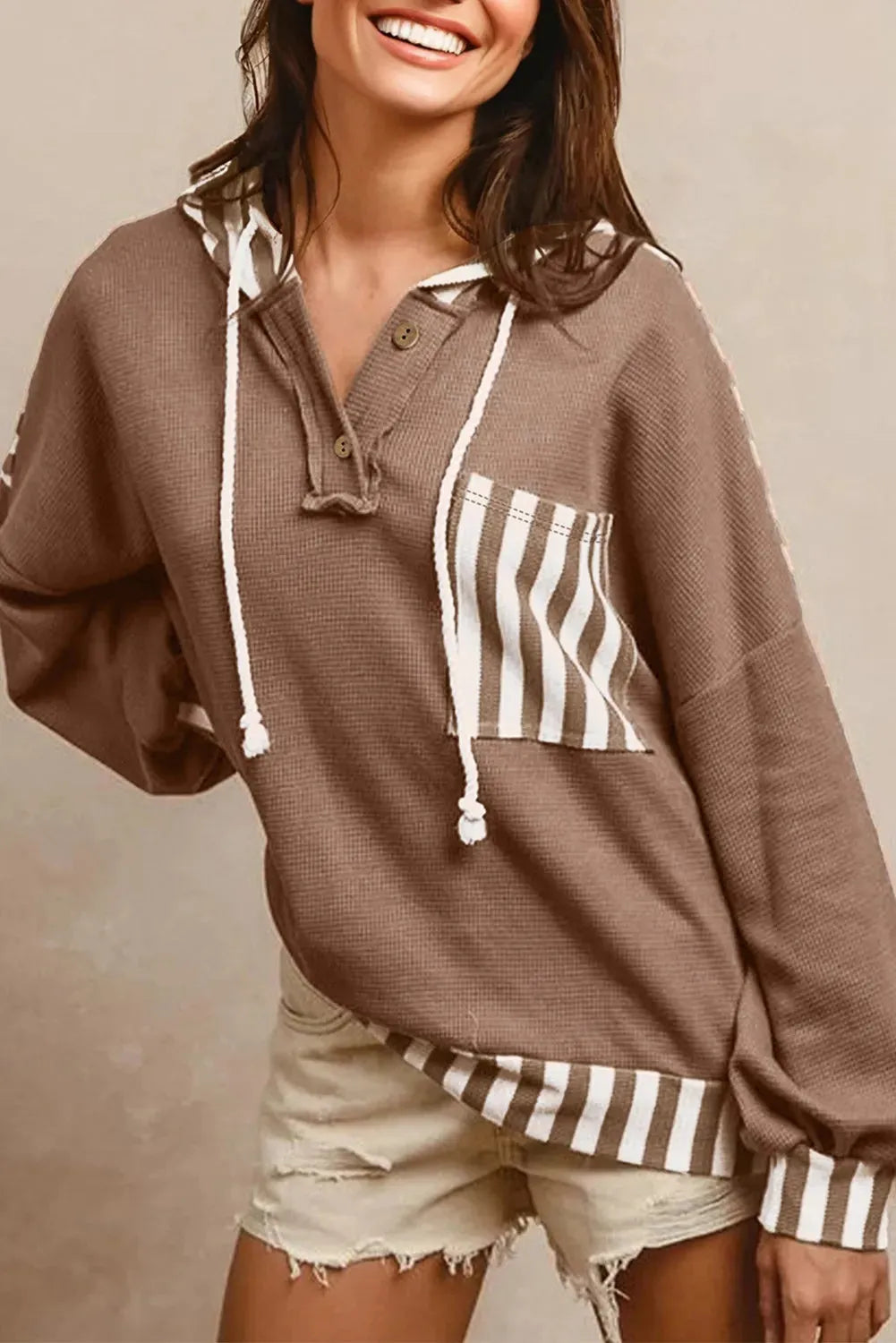 Straw yellow hoodie with waffle texture and striped patchwork design, showing front drawstring and button neck.