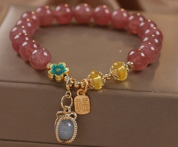 Red bracelet with strawberry quartz beads, alloy metal spacers, and rhinestone decorative details.