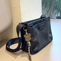 A small square crossbody bag in a cool retro style, made from textured Oxford cloth, shown on a person for scale.