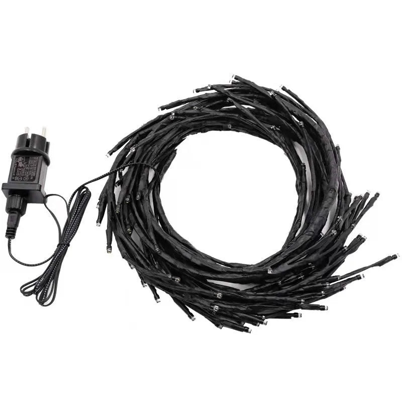 Flexible plastic willow vine LED garland light with warm white lights, shaped on a wall.