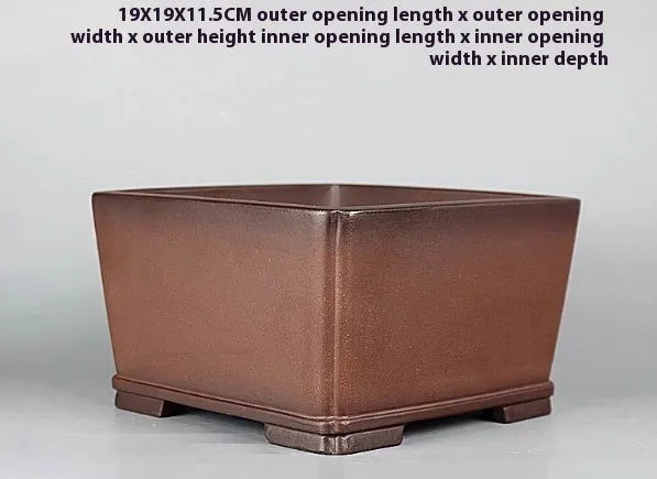Handmade brown antique-style purple clay flower pot for houseplants on a desk.