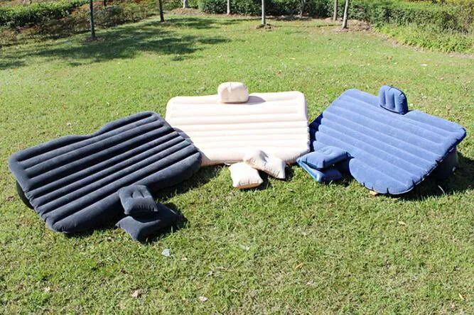 Black inflatable car bed with flocked surface and pillows set up in a car's back seats