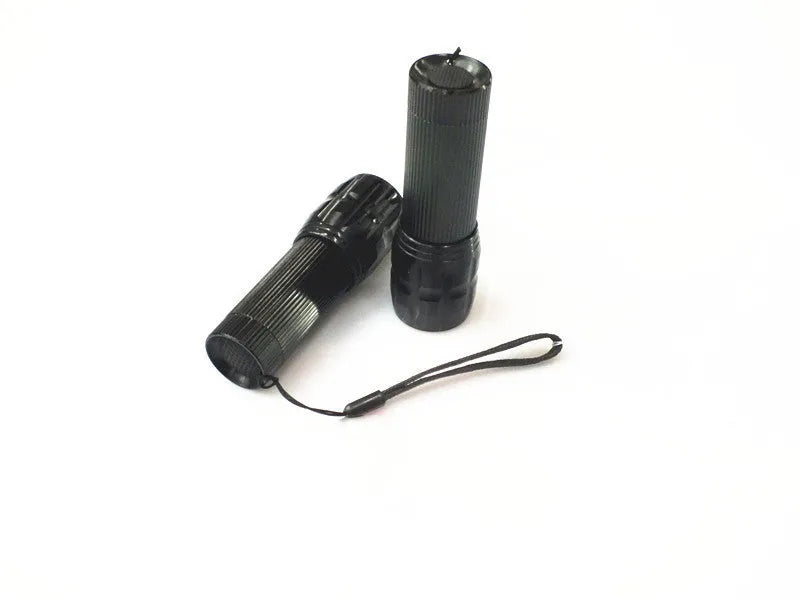 Black mini LED flashlight with telescopic head and tail push button switch on plain background