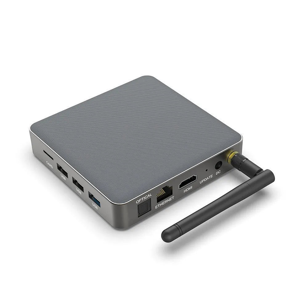 Black Android 8K TV set-top box with remote control, UK plug, and HDMI cable on a wooden surface.