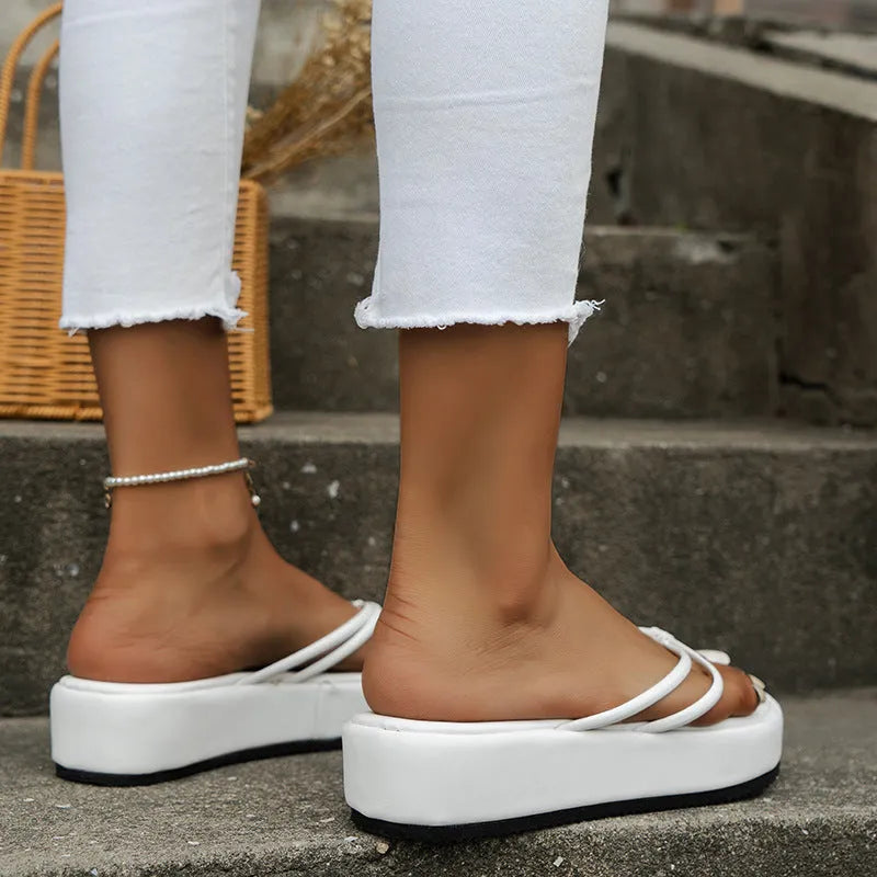 A pair of white herringbone-pattern flip-flops with a thick rubber sole, shown from above.