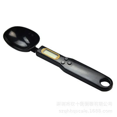 White digital kitchen spoon scale with LCD display showing 0.0g on a wooden table