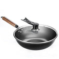 Black handmade traditional iron wok with a wooden handle on a stovetop.