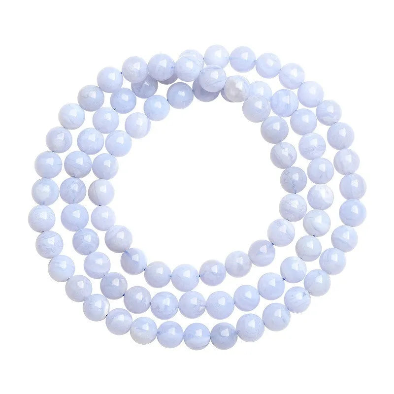 Close-up of a blue agate bracelet with scattered beads and striped spheres on a wrist.