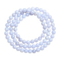 Close-up of a blue agate bracelet with scattered beads and striped spheres on a wrist.