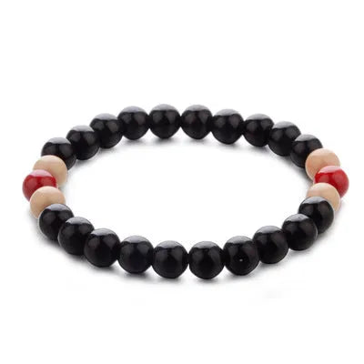 A natural lava stone bead bracelet with an ethnic design on a wrist, showing its porous texture for essential oils.
