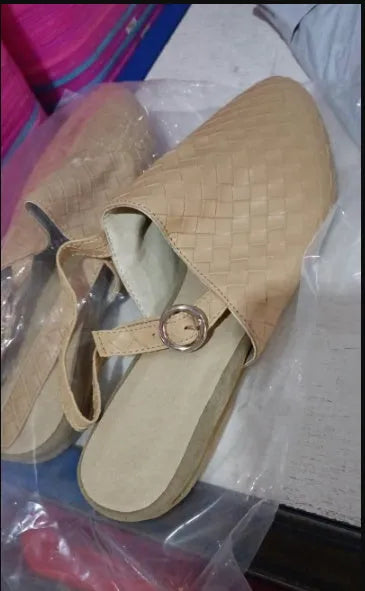 A pair of black baotou flat sandals with a buckle fastening and pointed toe on a plain background.