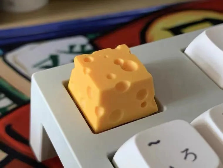 Close-up of a yellow resin cheese-shaped keycap for a mechanical keyboard.